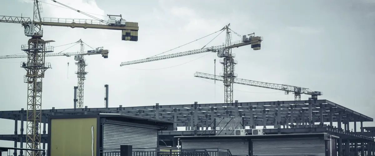A building under construction with cranes behind it