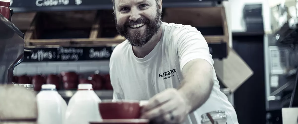 The owner of an independent cafe handing a cup across the counter